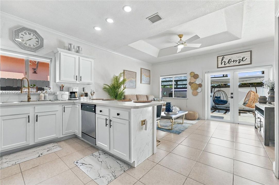 Kitchen featuring white shaker-style cabinetry, stone-finish countertops, stainless steel appliances, recessed ceiling lighting, and tile flooring