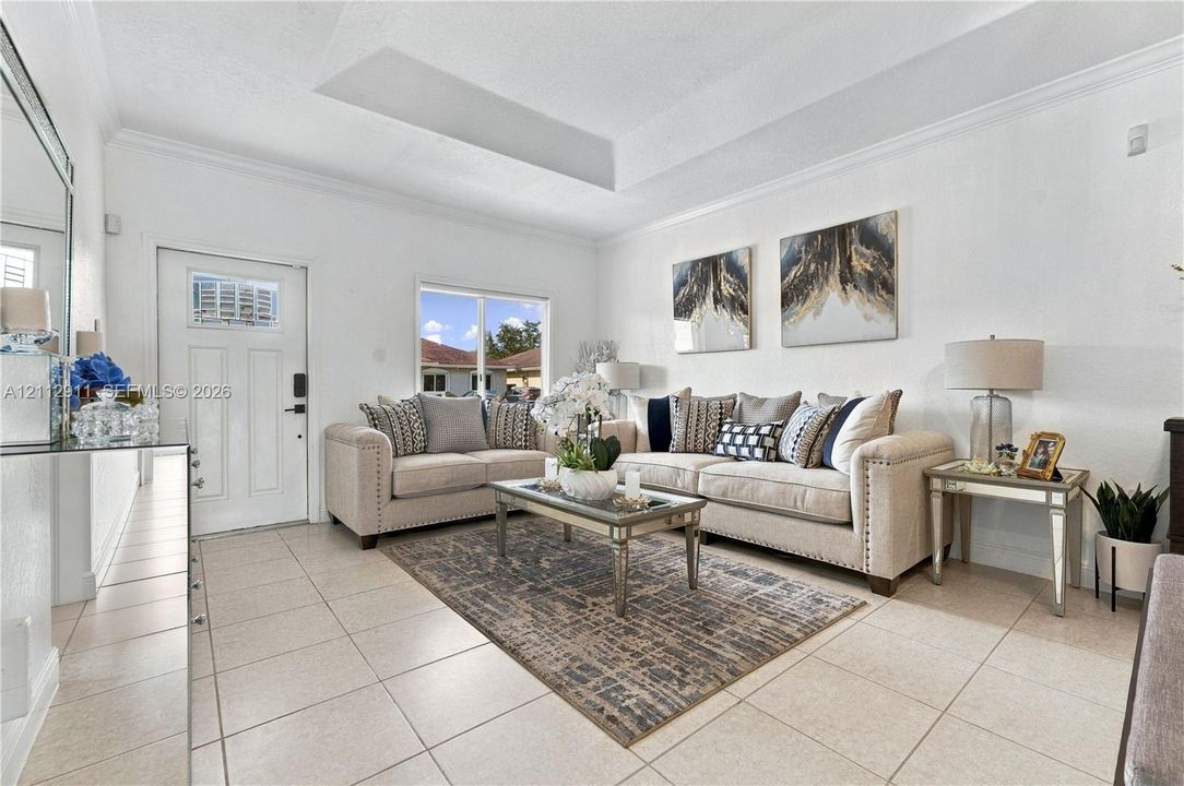 Interior space featuring ceramic tile flooring, a tray ceiling, crown molding, and a multi-panel entry door with an integrated window
