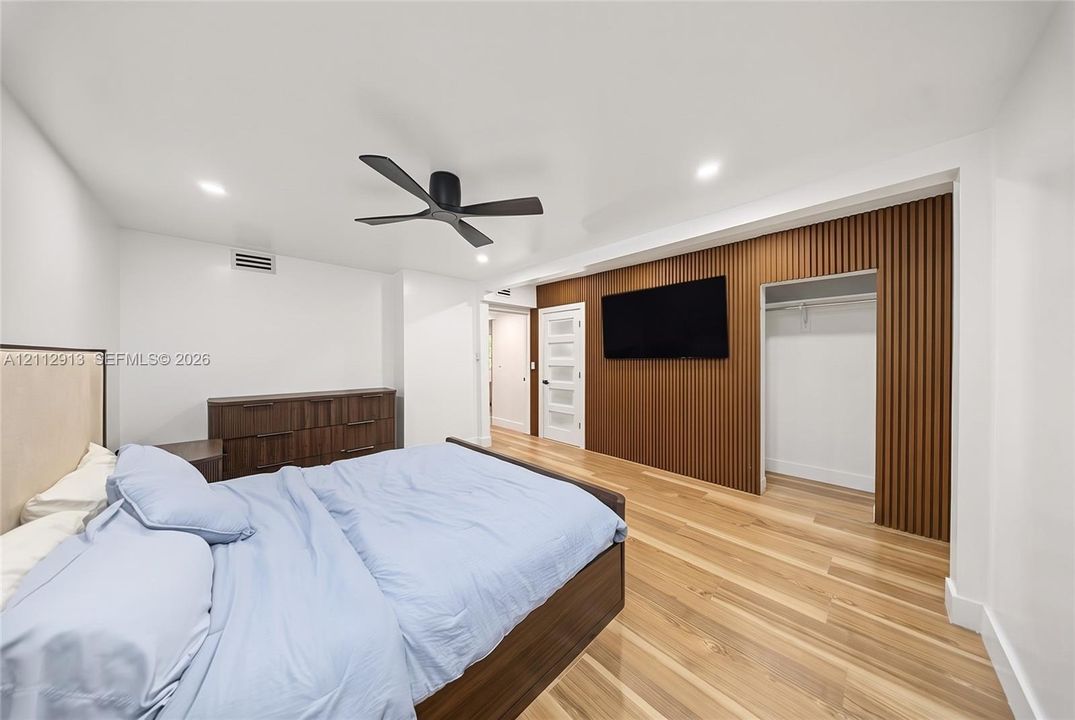 Interior room featuring wood-finish flooring, a wood-slat accent wall, recessed lighting, and a modern matte black ceiling fan