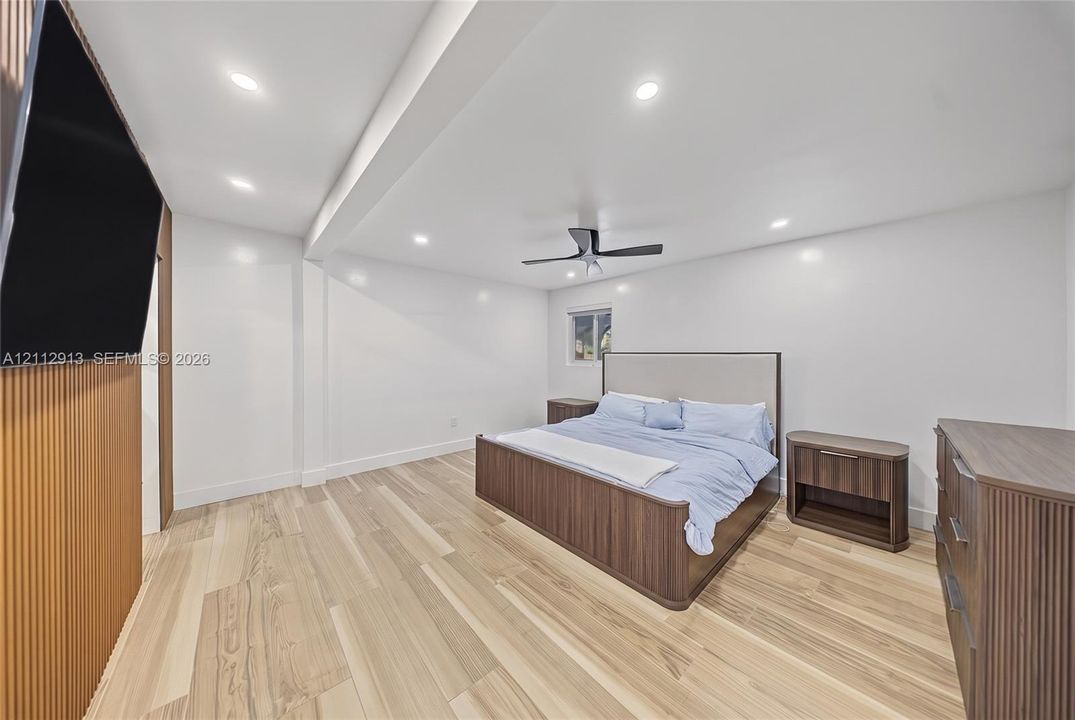 Room interior featuring wood-finish flooring, recessed lighting, a modern ceiling fan, and a vertical wood-slat accent wall