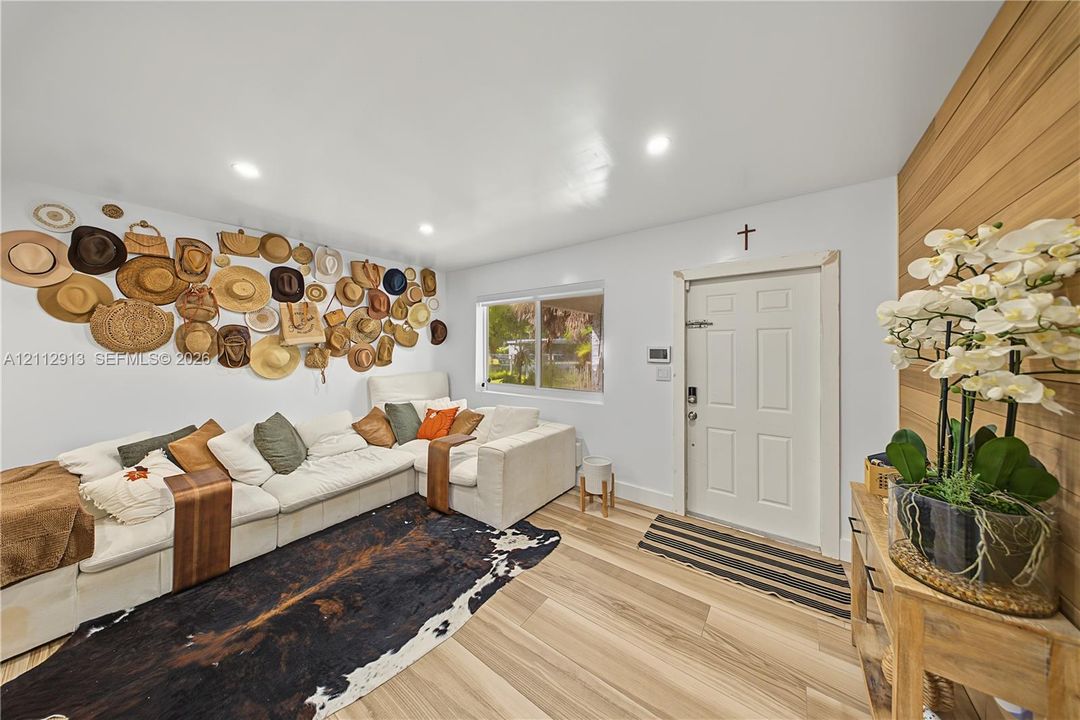 Wood-finish flooring, vertical wood-paneled accent wall, recessed lighting, and dual-pane window