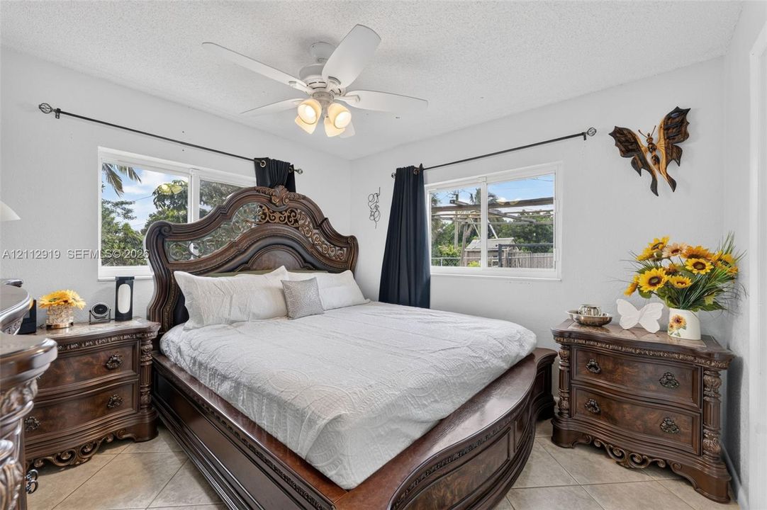 Neutral walls, light-toned tile flooring, and a ceiling fan with integrated lighting