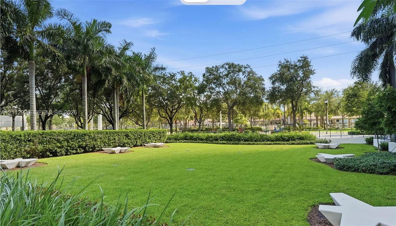 Expansive grounds featuring a manicured lawn, established landscaping, mature palm trees, and structural stone hardscaping