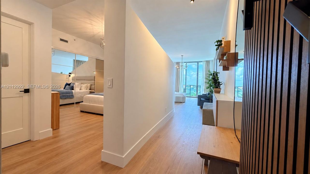 Interior featuring light-toned wood-finish flooring, floor-to-ceiling windows, recessed LED accent lighting, mirrored sliding closet doors, and vertical wood-slat wall paneling