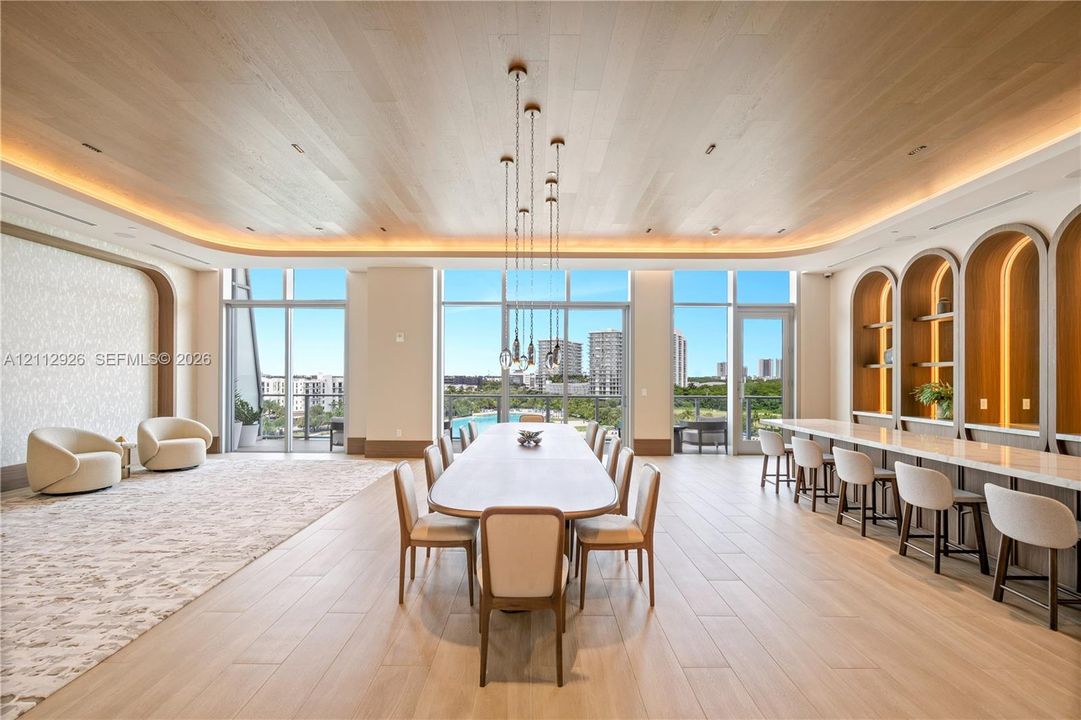 Expansive space featuring wood-finish ceiling planks, recessed ambient cove lighting, floor-to-ceiling windows, and arched built-in shelving with integrated lighting