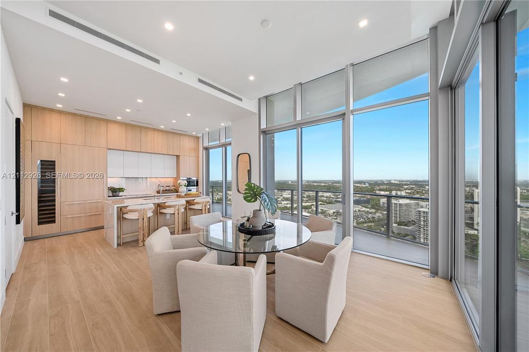 Floor-to-ceiling glass walls, integrated light-toned wood cabinetry, built-in wine refrigeration, wood-finish flooring, and recessed ceiling lighting