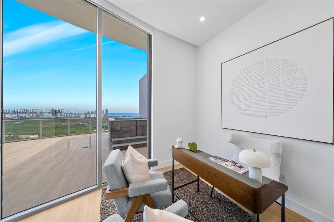 Floor-to-ceiling glass sliding doors, wood-finish flooring, and a private balcony with metal and glass railing, featuring urban and water scenery