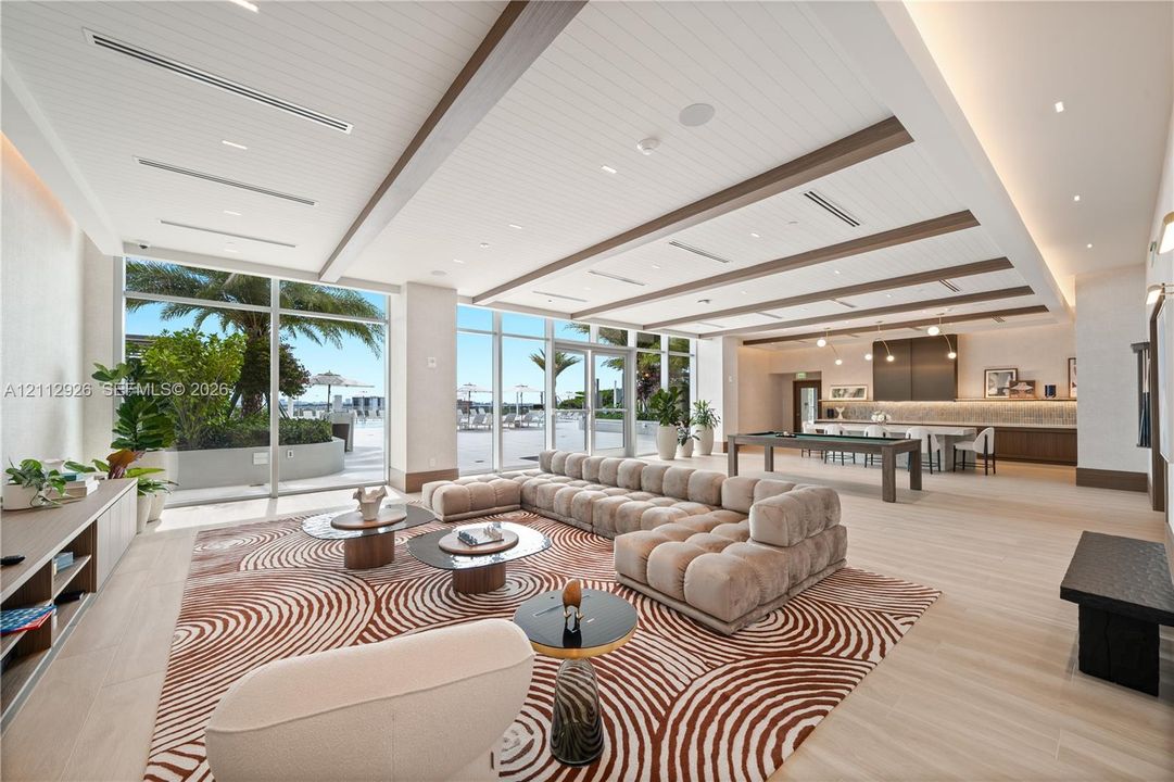 Open-concept interior featuring floor-to-ceiling glass walls, coffered ceilings with wood-finished beams, integrated recessed lighting, and wood-finish flooring