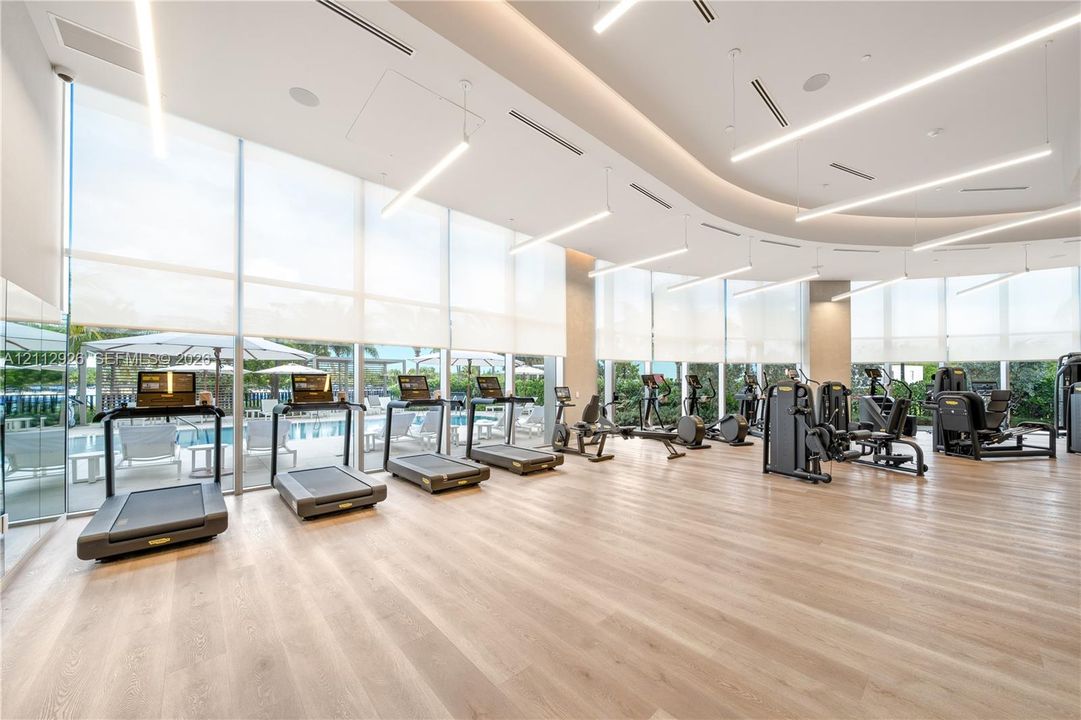 Fitness facility featuring floor-to-ceiling windows, wood-finish flooring, recessed lighting, and integrated ceiling speakers