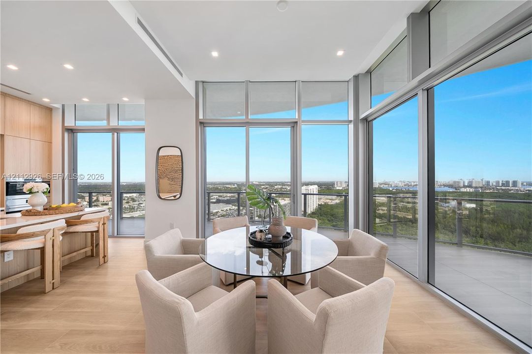 Floor-to-ceiling glass walls, wood-finish flooring, custom wood cabinetry, integrated built-in appliances, and expansive balcony space