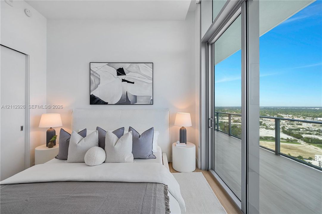 Floor-to-ceiling glass sliding doors, private balcony with metal railing, and neutral-tone flooring