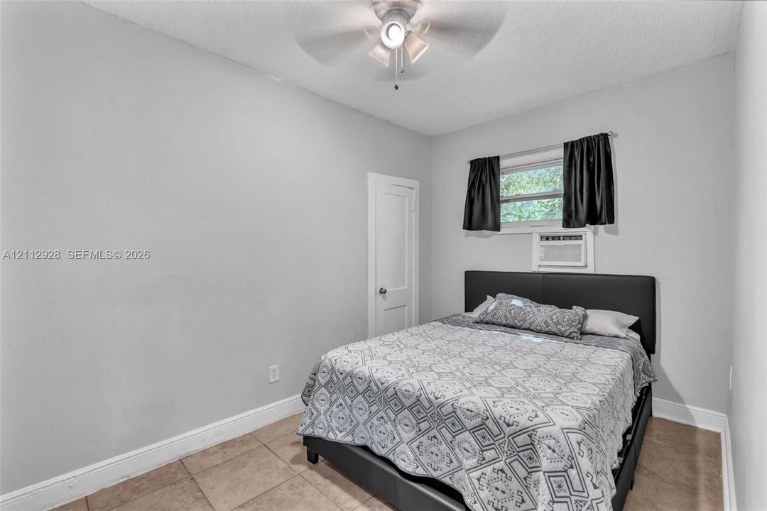 Neutral-toned interior featuring tiled flooring, a single-panel interior door, and a ceiling-mounted light fixture with fan