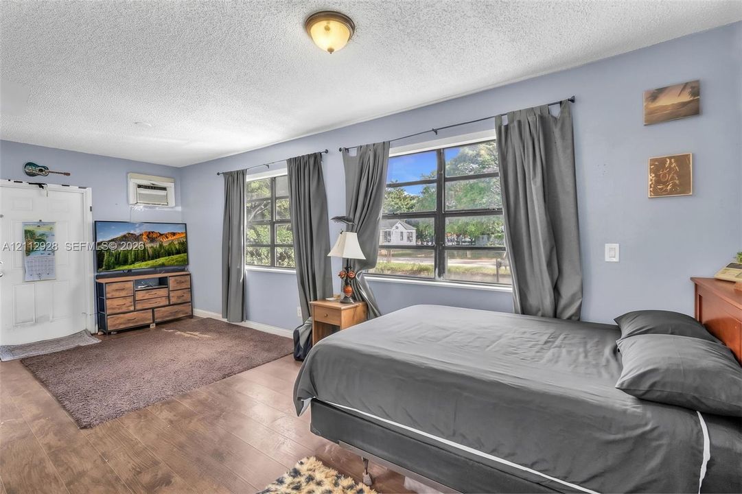 Room featuring wood-finish flooring, two large multi-pane windows, and a flush-mount ceiling light fixture