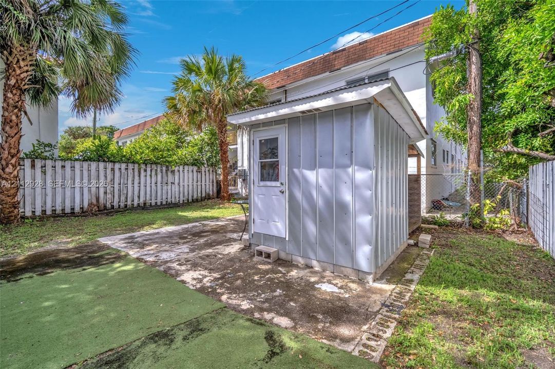 Backyard area featuring a metal storage shed on a concrete pad, fenced perimeter, and synthetic turf