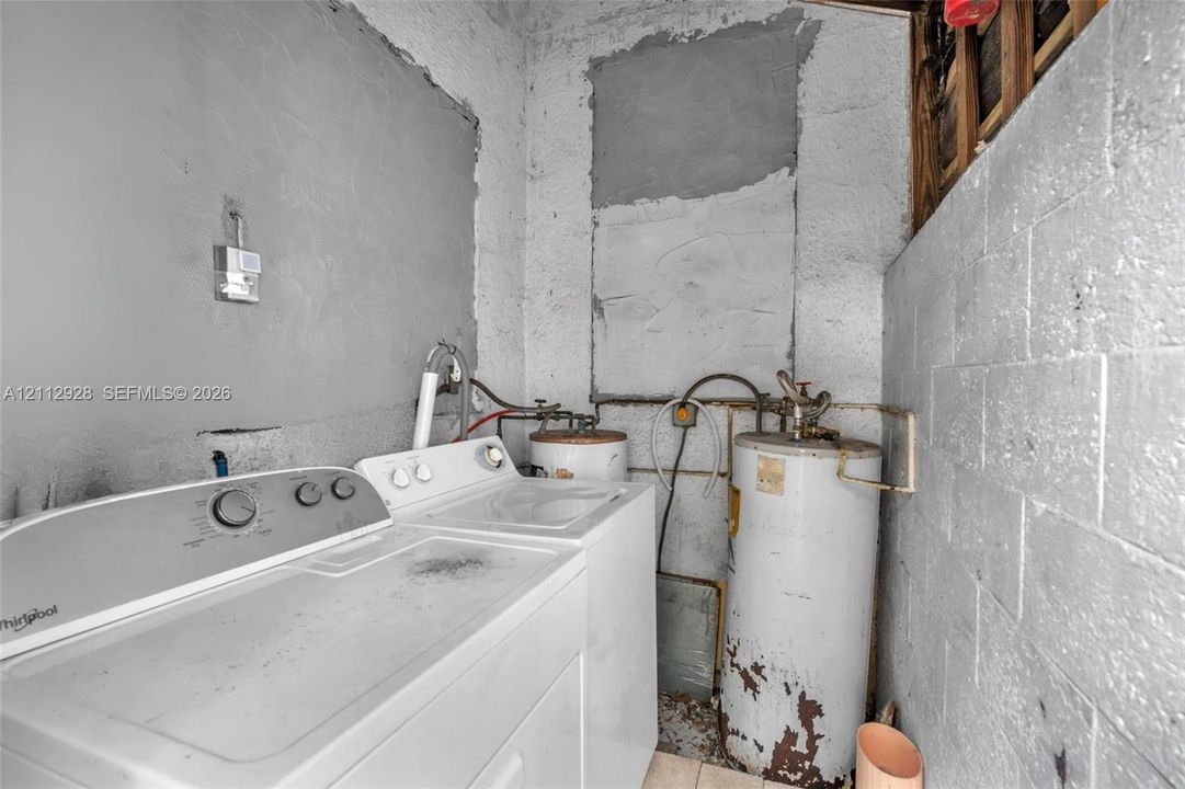 Utility area featuring exposed concrete block walls and a vertical water heater