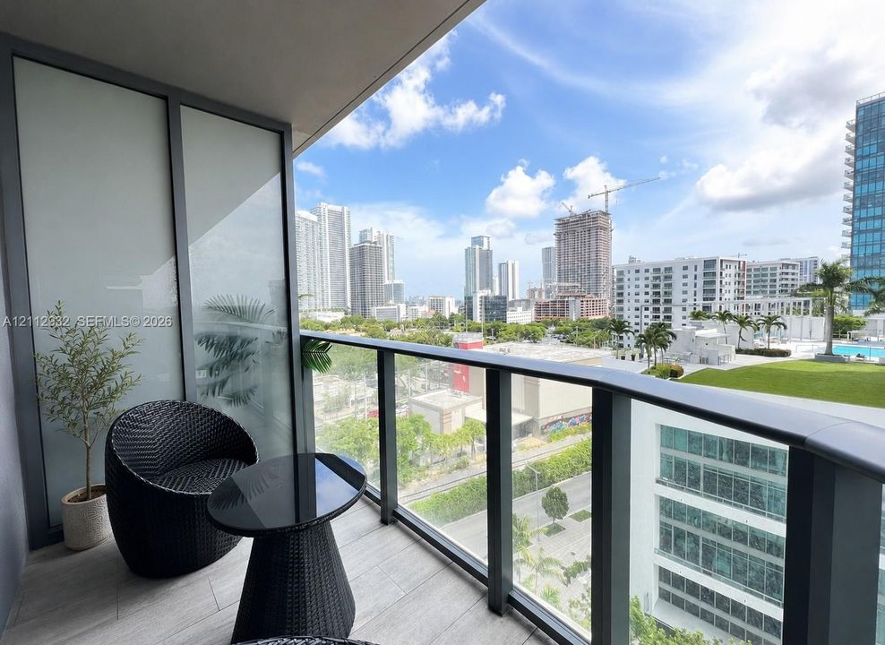 Private covered balcony featuring ceramic tile flooring, a glass panel railing, and frosted privacy screening