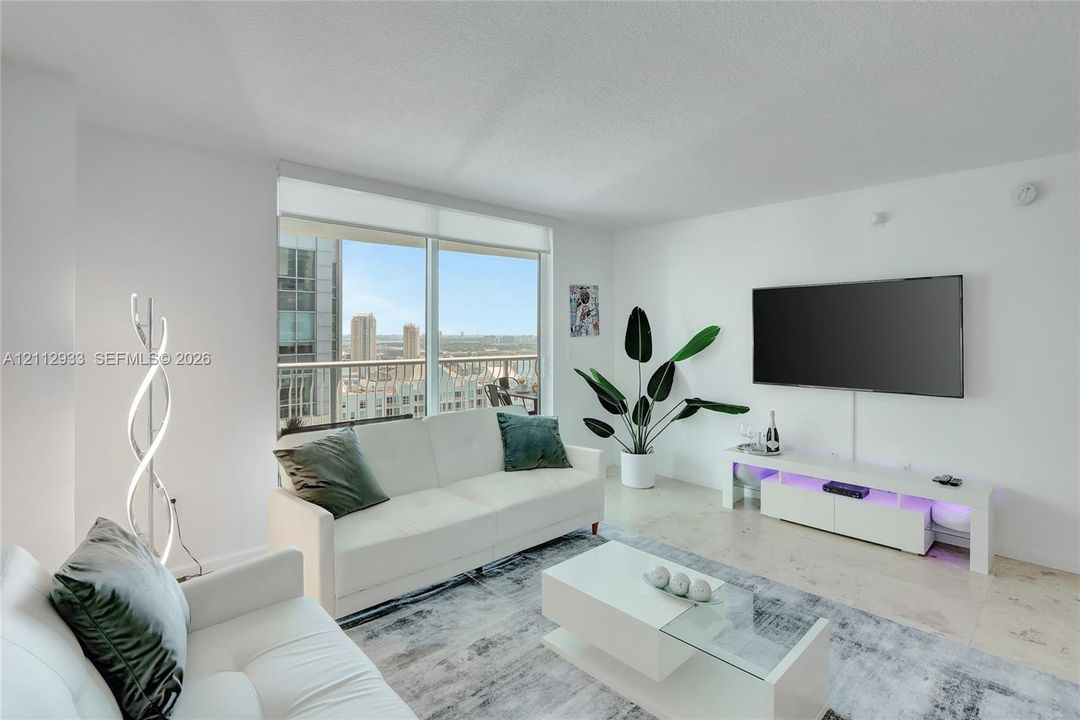 Living area featuring floor-to-ceiling windows, a private balcony, and light-toned tile flooring