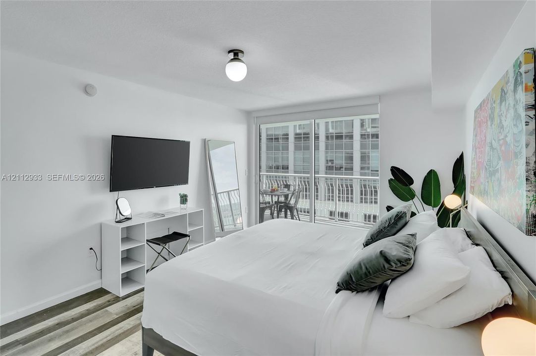 Wood-finish flooring, sliding glass door with balcony access, and globe-style ceiling lighting