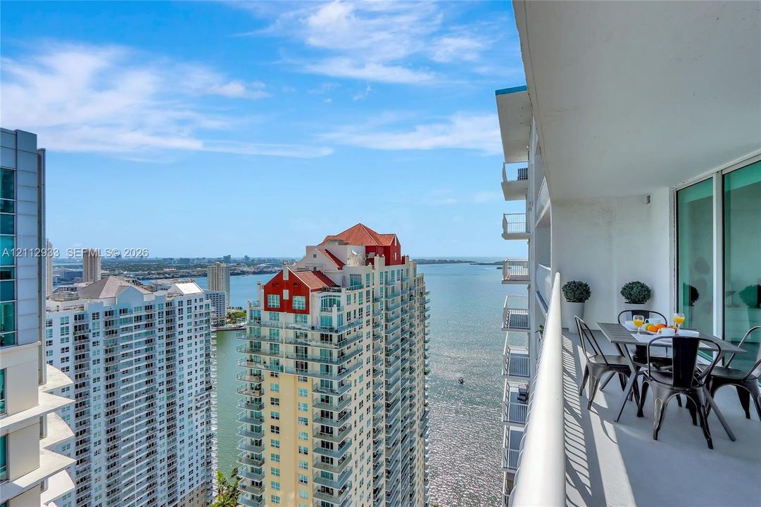 Covered balcony with a solid concrete floor and a high-profile metal railing overlooking an urban waterfront setting