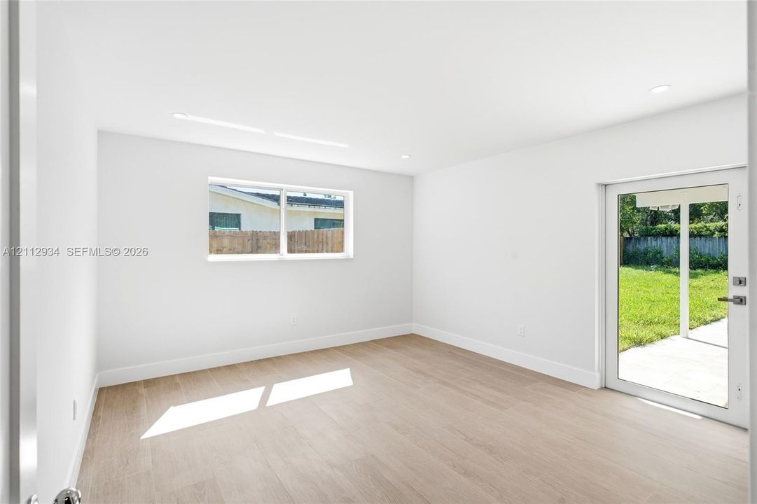 Interior room featuring wood-finish flooring, recessed lighting, a horizontal window, and a full-glass exterior door
