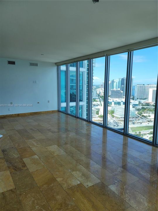Floor-to-ceiling windows with expansive urban outlooks and natural stone tile flooring