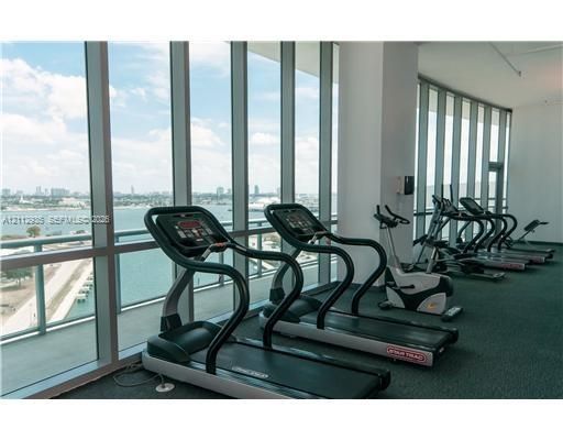 Fitness center featuring floor-to-ceiling windows and extensive water and city skyline surroundings