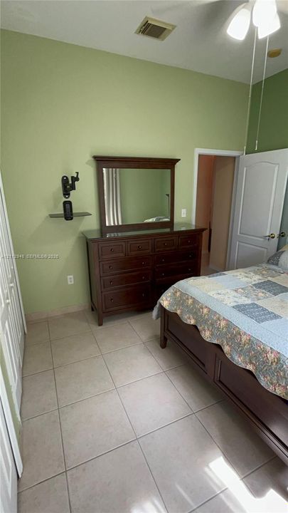 Room interior featuring light-colored tile flooring, vaulted ceilings, a ceiling fan with integrated lighting, and a multi-panel door