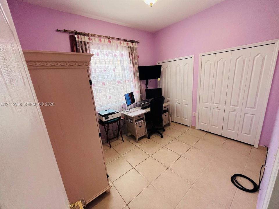 Ceramic tile flooring, dual bi-fold closet doors, and a single window with decorative curtain rod hardware