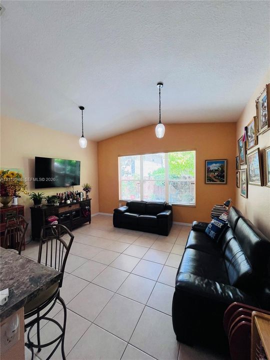Vaulted ceilings, neutral tile flooring, multi-pane windows, and dual pendant light fixtures