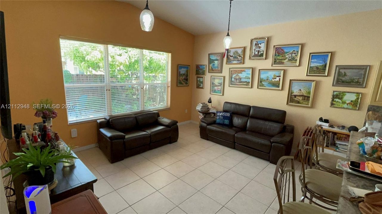 Vaulted ceilings with pendant lighting, large multi-pane windows, and light-toned tile flooring