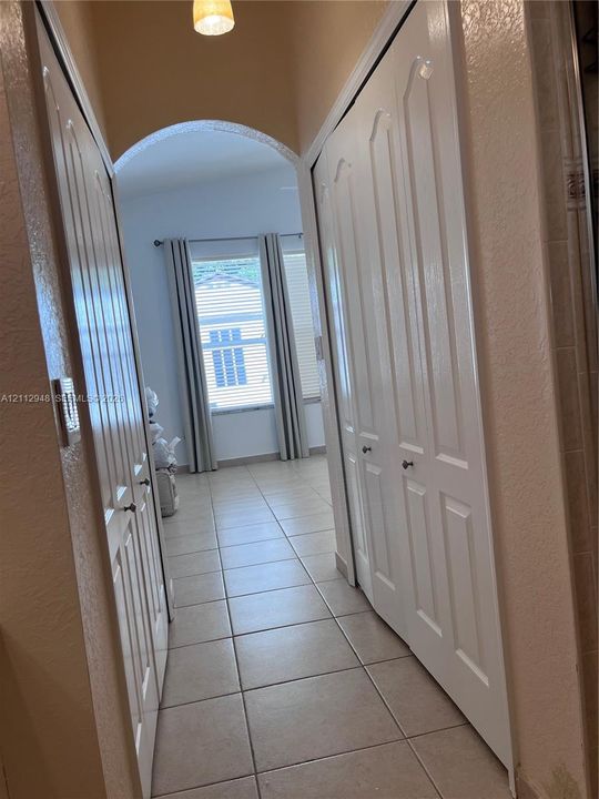 Hallway featuring tiled flooring, an arched ceiling detail, and dual floor-to-ceiling closets with paneled doors