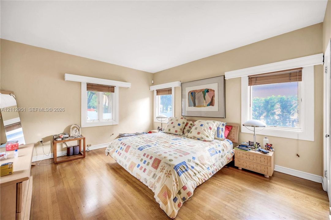Wood-finish flooring, neutral wall color, and multiple windows with white trim and headers