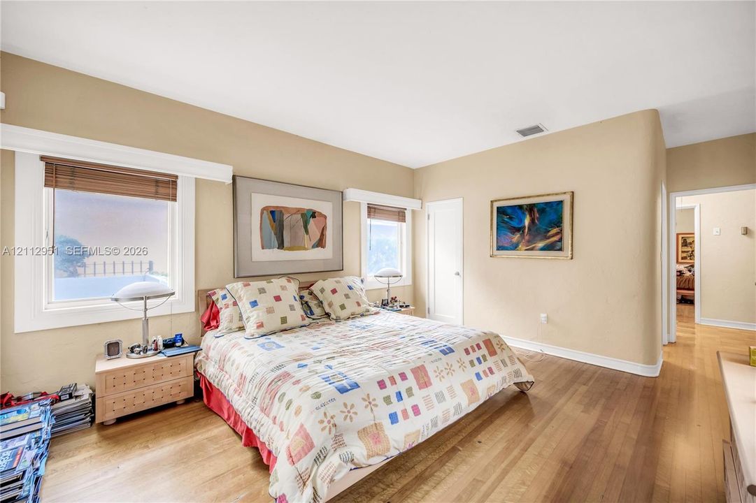 Room featuring wood-finish flooring, two windows with wood blinds, and a rounded wall corner