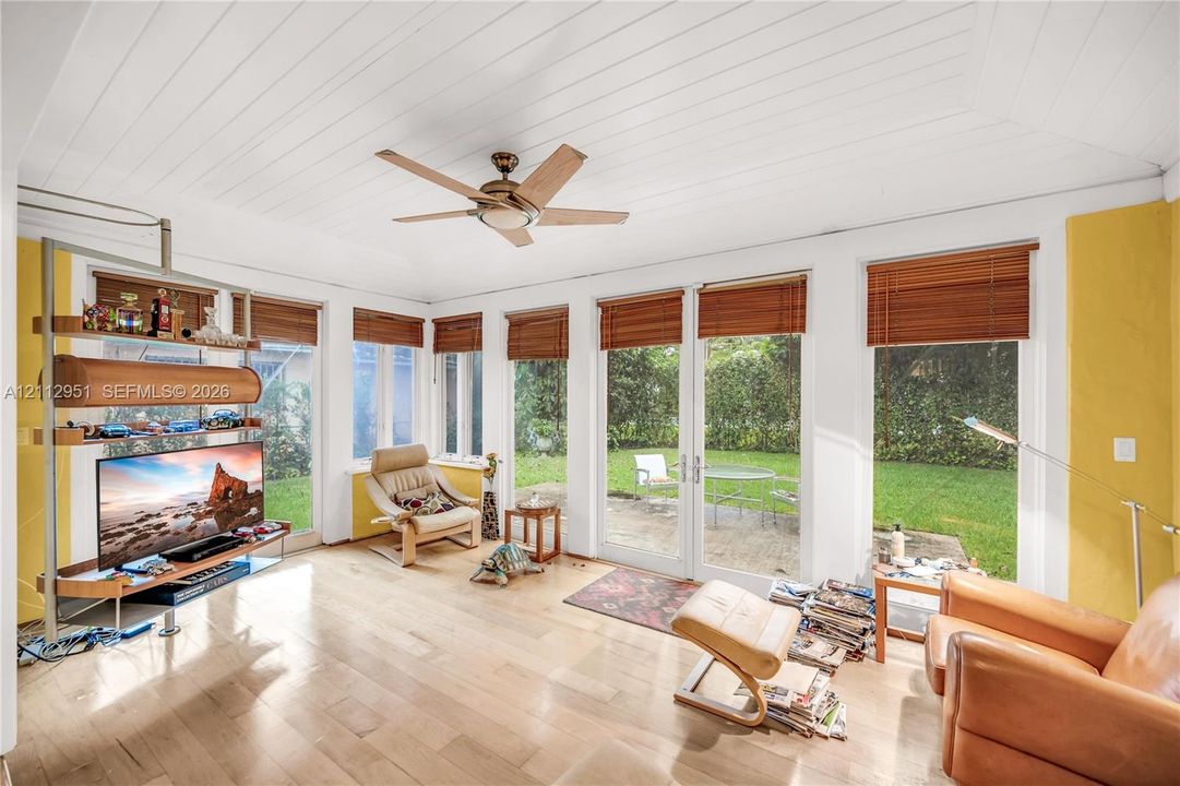 Sunroom with tongue-and-groove vaulted ceilings, wood-finish flooring, ceiling fan, and extensive floor-to-ceiling windows featuring integrated French doors