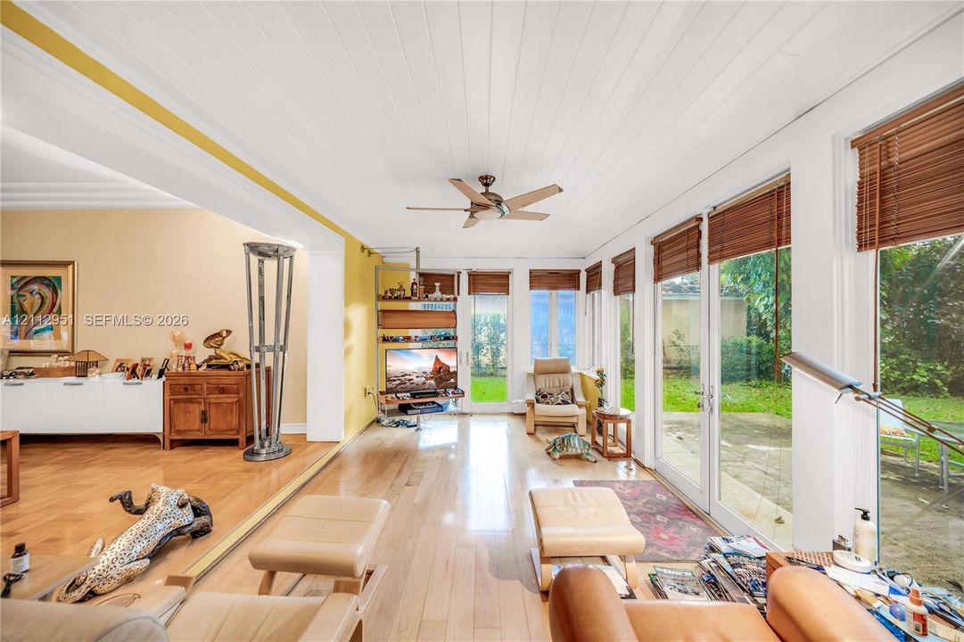 Living space featuring wood-finish flooring, wood-paneled ceiling, ceiling fan, and floor-to-ceiling glass doors with direct access to the exterior