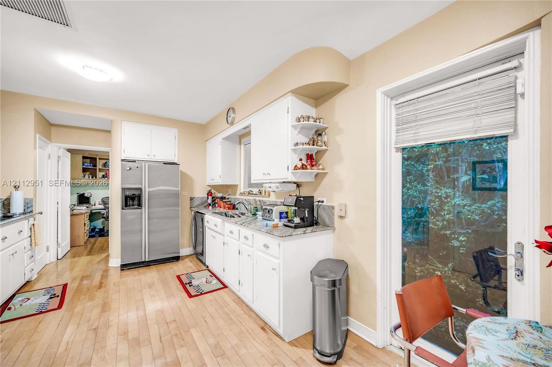 Kitchen featuring white cabinetry, stone countertops, wood-finish flooring, stainless steel side-by-side refrigerator, and a full-light glass door