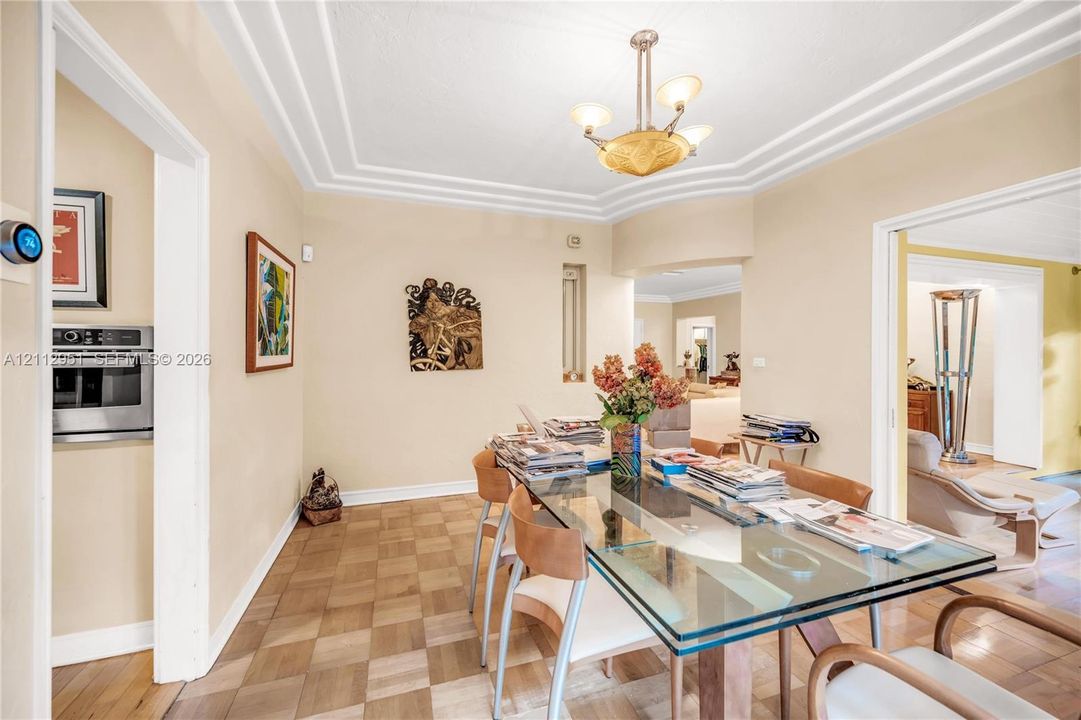 Parquet wood flooring, tiered tray ceiling, three-arm central light fixture, and built-in stainless steel oven