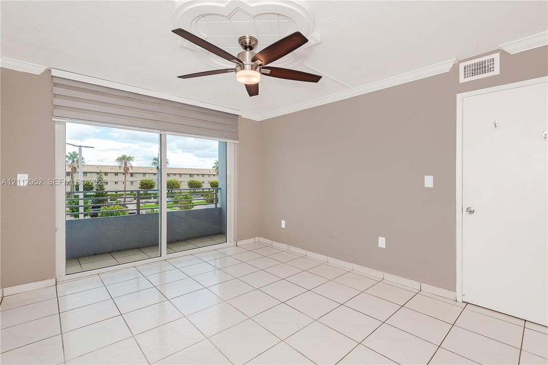 Ceramic tile flooring, ceiling fan with integrated lighting, decorative ceiling medallion, crown molding, and sliding glass door with horizontal shade