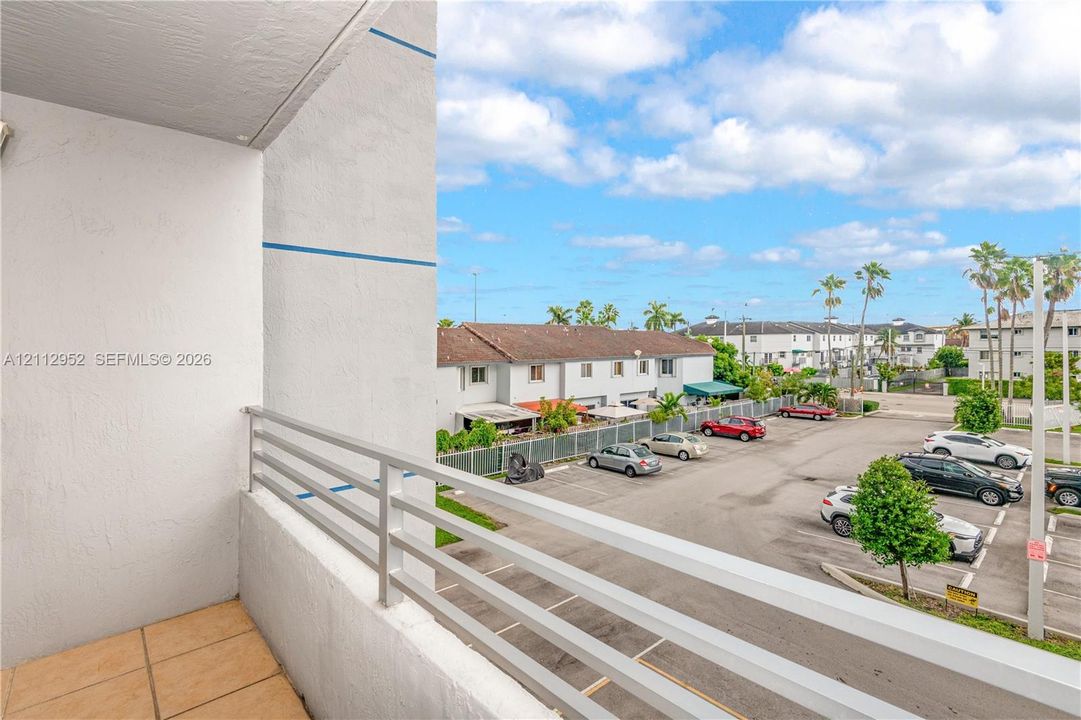 Covered exterior balcony with tiled flooring and horizontal metal railing