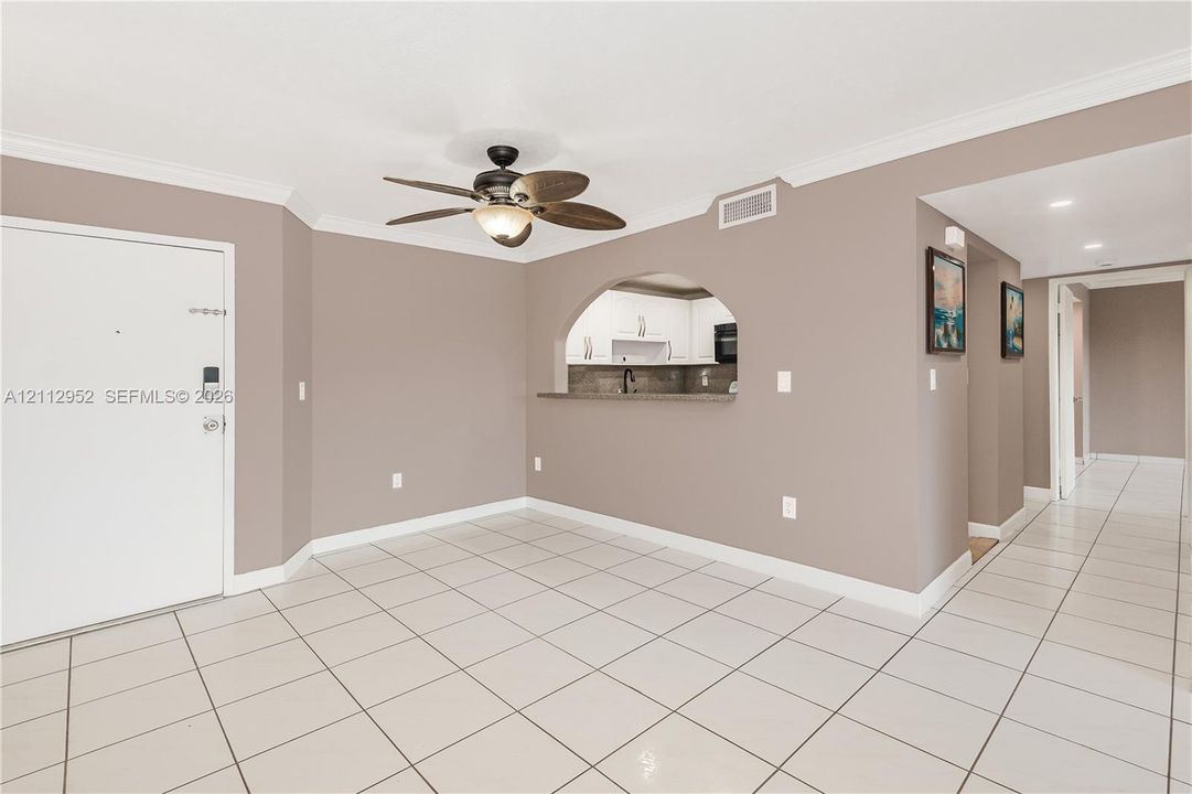 Ceramic tile flooring, arched wall pass-through, and ceiling fan with integrated light fixture