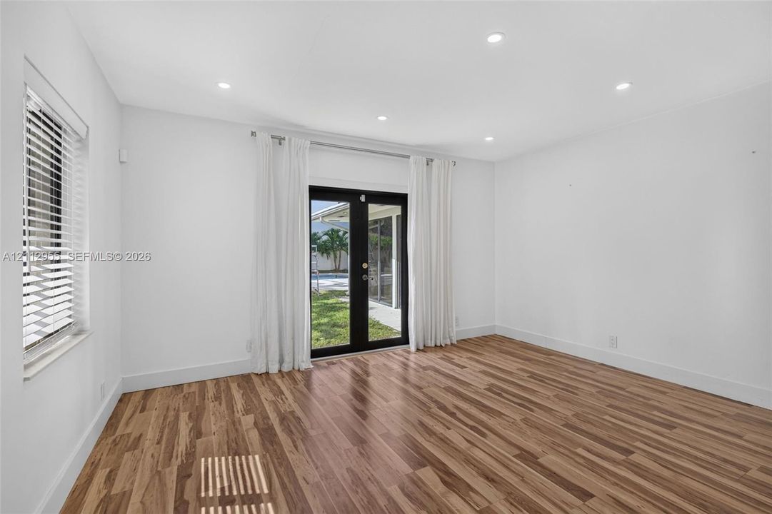 Wood-finish flooring, recessed lighting, and black-framed glass French doors