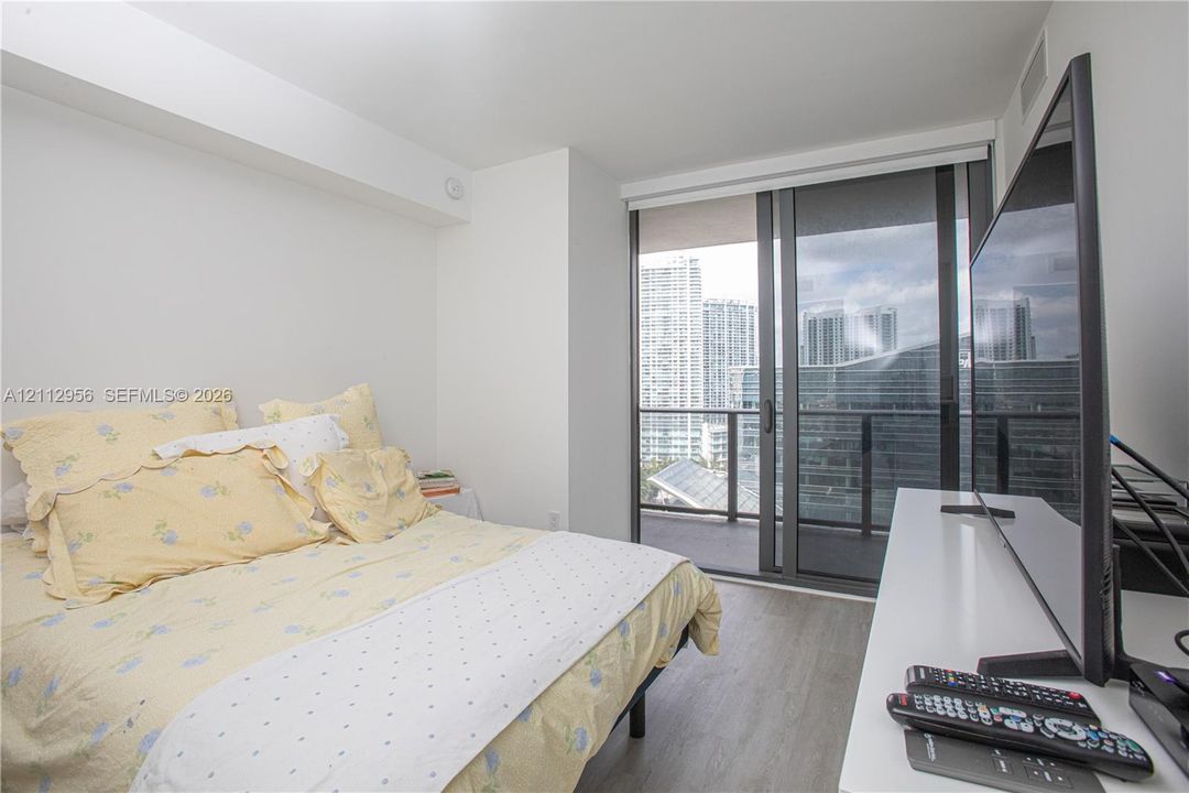 Wood-finish flooring, floor-to-ceiling sliding glass doors, and a private balcony