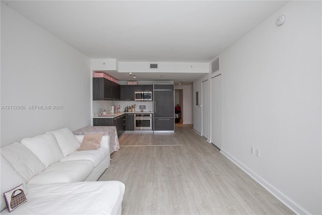 Kitchen featuring dark cabinetry, stainless steel appliances, and wood-finish flooring