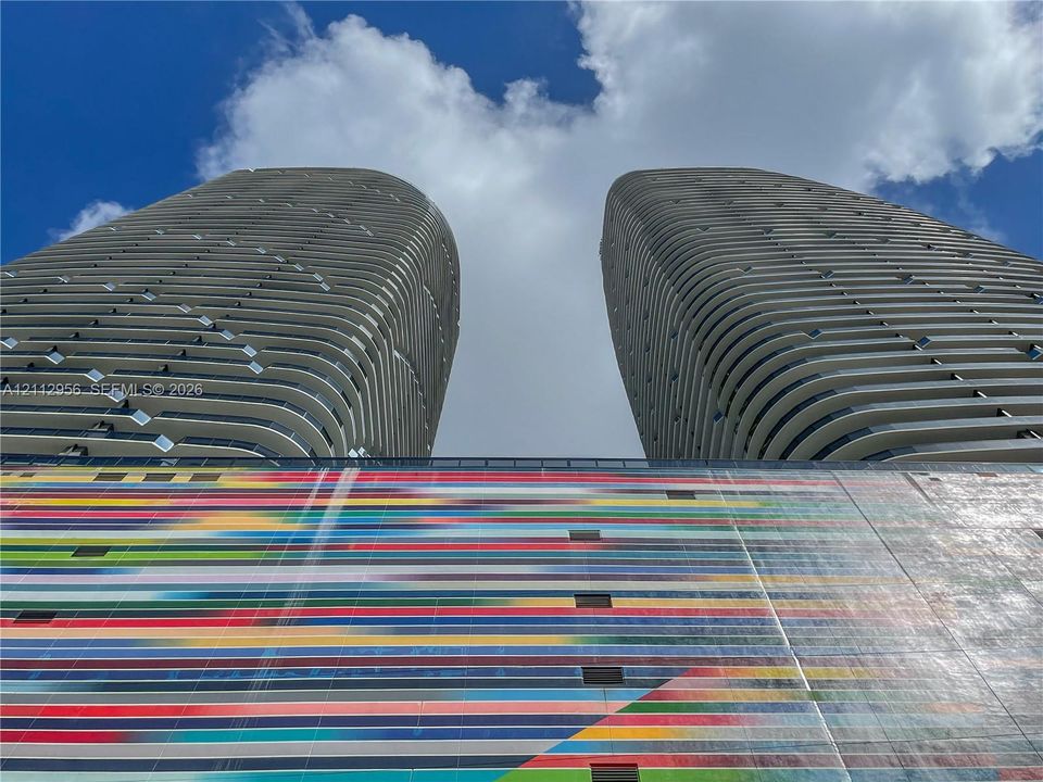 High-rise towers featuring curvilinear architecture, private balconies, and an expansive exterior wall mural