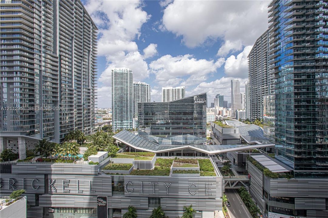 High-rise urban landscape featuring expansive floor-to-ceiling glass facades, metal exterior paneling, integrated green roof systems, and multi-level structural walkways