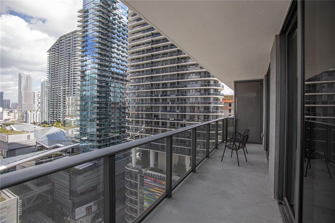 Covered balcony featuring concrete flooring and a glass-paneled metal railing