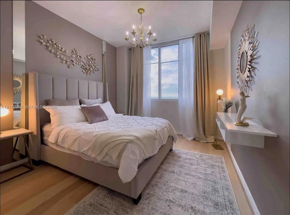 Expansive window with natural light, wall-mounted floating shelf, wood-finish flooring, and multi-arm chandelier