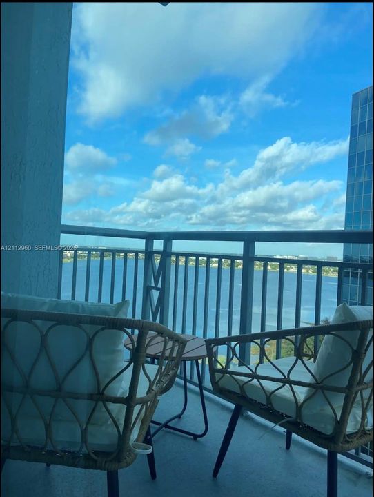 Covered balcony featuring metal railings and concrete flooring with water and skyline scenery