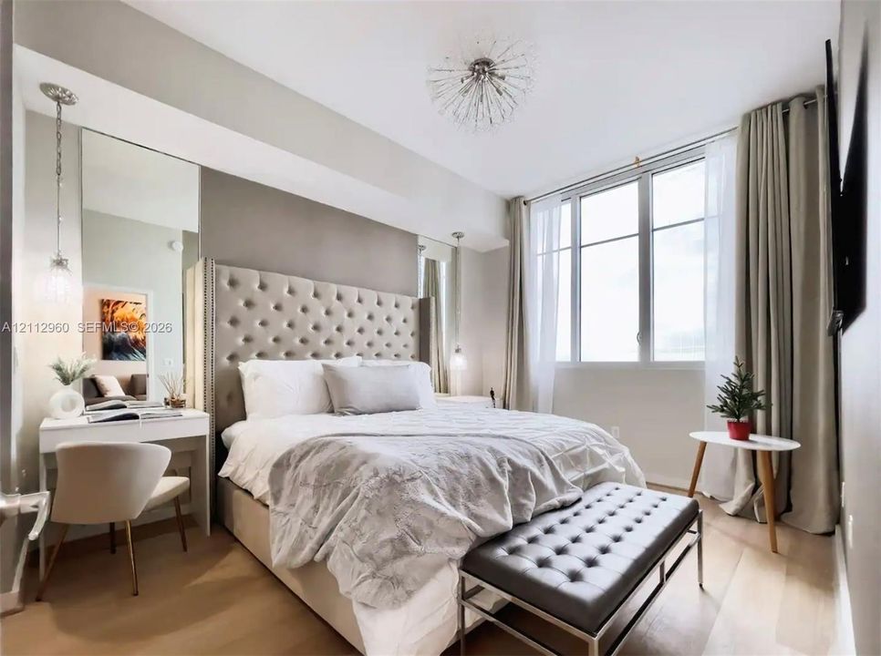 Bedroom featuring wood-finish flooring, floor-to-ceiling windows, integrated mirror panels, and contemporary spherical chandelier lighting