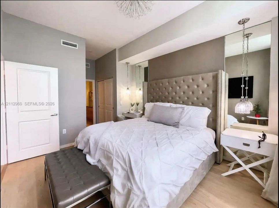 Neutral wall tones paired with light wood-finish flooring, floor-to-ceiling mirror paneling, and glass pendant lighting fixtures